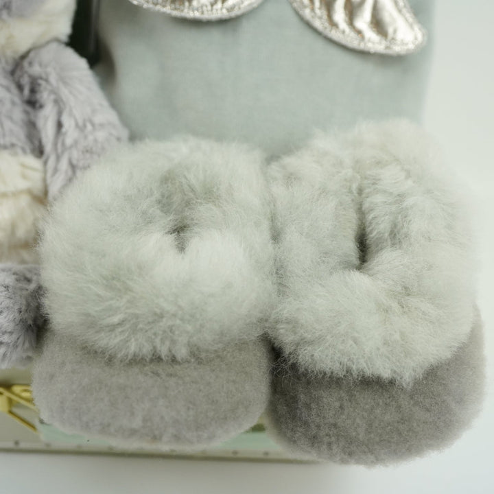 luxury neutral baby hamper in luxury baby keepsake suitcase in pale green with velour angel wings sleepsuit, organic baby toiletries, soft grey alpaca baby slippers and grey and white soft panda toy 