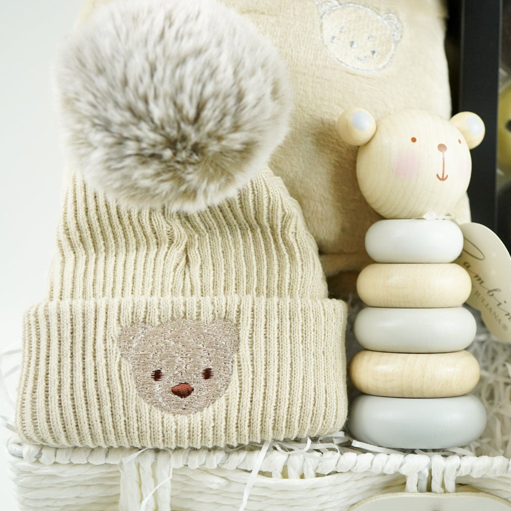 neutral baby and mum gift hamper includes neutral coloured baby dressing gown with cute ears, biscuit coloured baby pompom hat with teddy embroidery, wooden stacking toy, biscuit coloured baby booties, chocolates , milestone cards and bamboo cellular blanket 