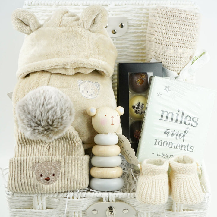 neutral baby and mum gift hamper includes neutral coloured baby dressing gown with cute ears, biscuit coloured baby pompom hat with teddy embroidery, wooden stacking toy, biscuit coloured baby booties, chocolates , milestone cards and bamboo cellular blanket 