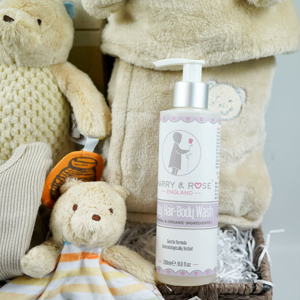 Grey paper rope neutral baby hamper with winnie the pooh comforter and pram toy, baby hooded dressing gown in caramel colour and baby sleepsuit, baby organic bubbles, non alcoholic freixenet and milestone cards 