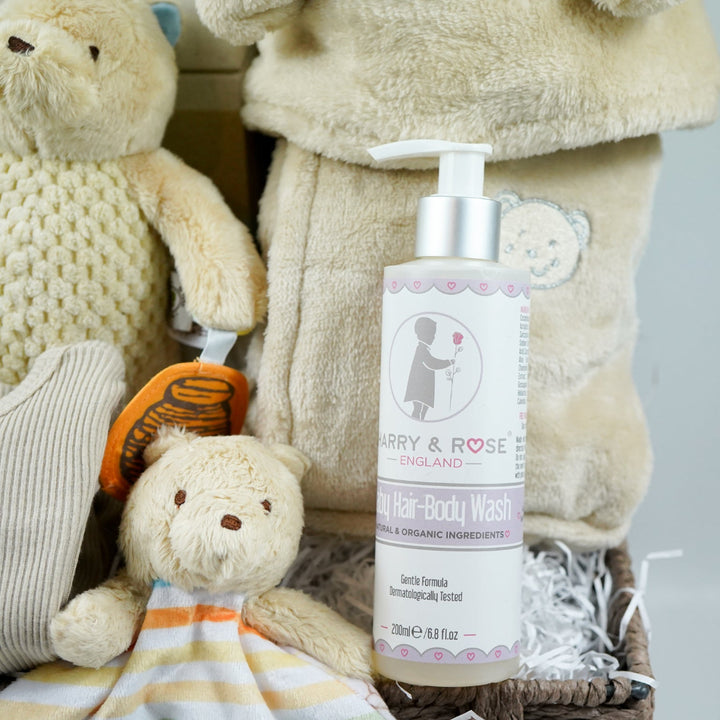 Grey paper rope neutral baby hamper with winnie the pooh comforter and pram toy, baby hooded dressing gown in caramel colour and baby sleepsuit, baby organic bubbles, non alcoholic freixenet and milestone cards 