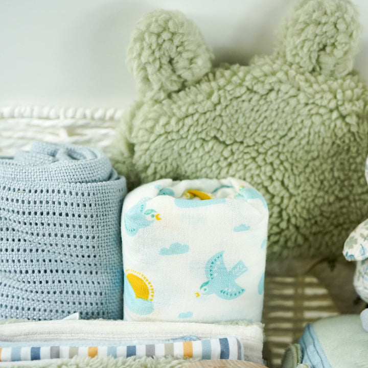 miffy themed baby hamper with green soft book, activity cube in pastel shades of green, white and blue, miffy soft rattle and matching comforter, rain rattle, blue cellular blanket, white muslin swaddle with bluebirds, fluffy green hat with ears and matching booties 