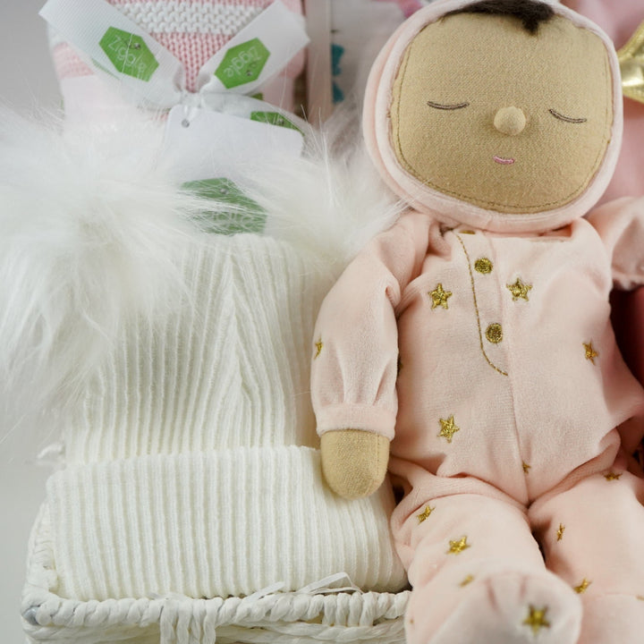 baby girl gift hamper with pink dozy dinkum soft musical doll. baby blanket , white fluffy hat, pink luxury candle, soft luxury baby outfit and swaddle in white with pink butteflies 