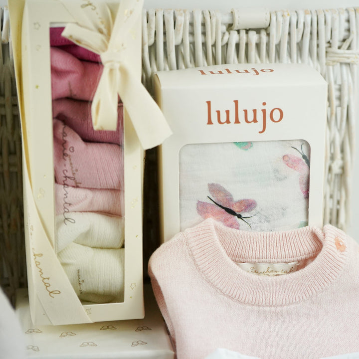 luxury baby girl gift hamper with luxury knitted baby girl outfit in pink, steiff rabbit with pink tutu, luxury hairbrush in a box, box of luxury socks, baby white swaddle with butterflies , luxury candle, white body suit with embroidered collar