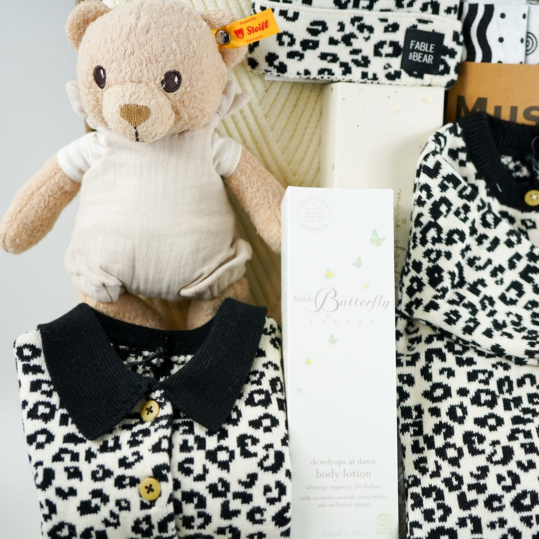 organic baby hamper with cream and black leopard prink knitted romper and  cardigan and matching hat in organic cotton, organic cotton cream blanket, organic steiff teddy, organic toiletries , organic black and white muslins and wooden sutainable hairbrush