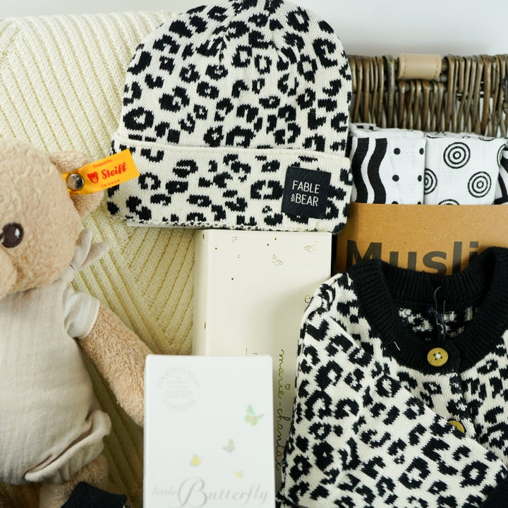 organic baby hamper with cream and black leopard prink knitted romper and  cardigan and matching hat in organic cotton, organic cotton cream blanket, organic steiff teddy, organic toiletries , organic black and white muslins and wooden sutainable hairbrush