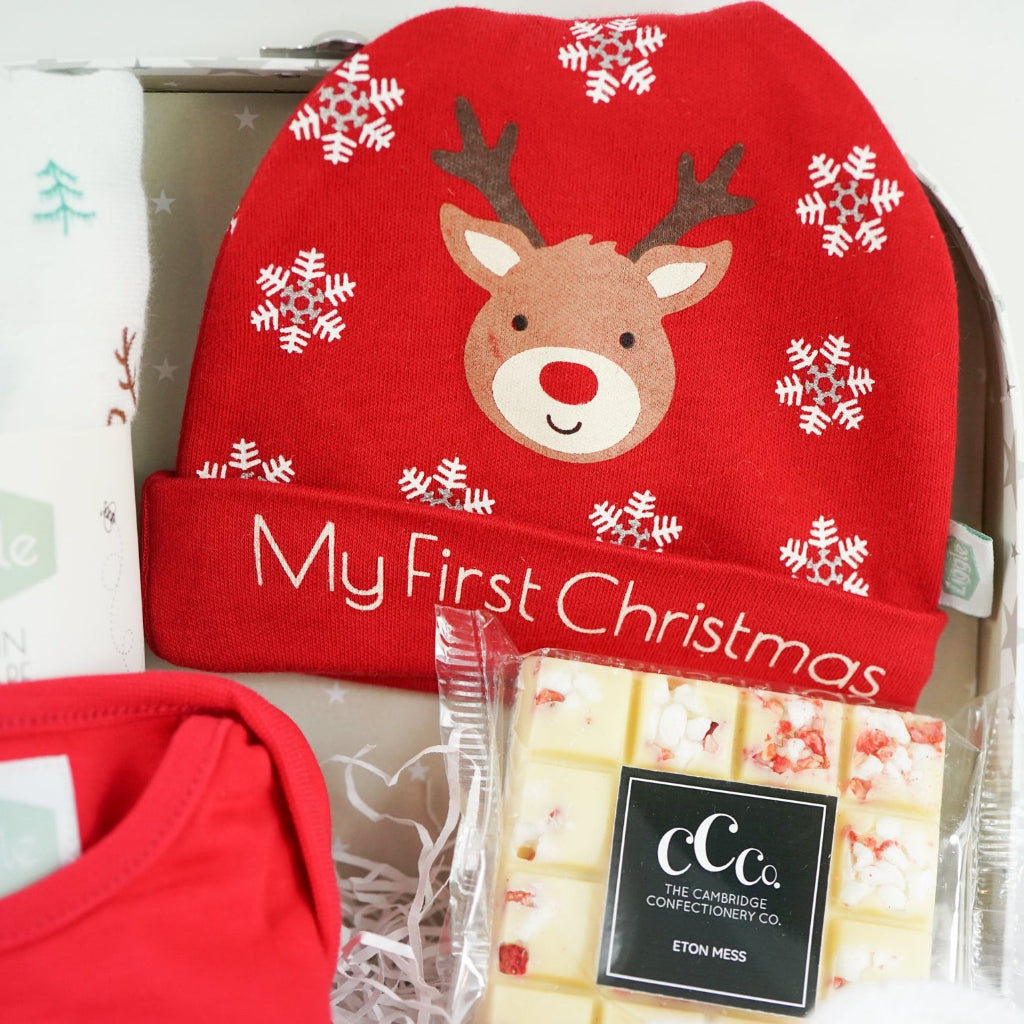 Baby gift set with red 'My First Christmas' shirt, socks, and booties in a decorative box.