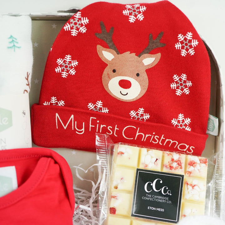 Baby gift set with red 'My First Christmas' shirt, socks, and booties in a decorative box.