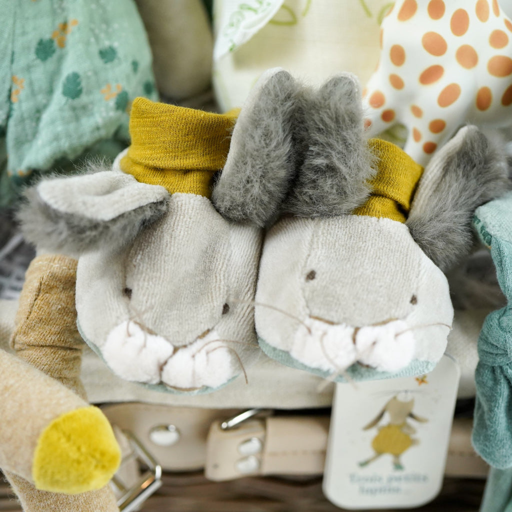 Luxury baby hamper with green hooded baby towel with ears, soft grey rabbit in green clothing set, rabbit slippers, cream and green baby swaddle, baby toiletries, green rabbit comforter, sophie la girafe teether toy, white baby sleepsuit with grey mice and magnetic fastenings all in a natural hamper basket 