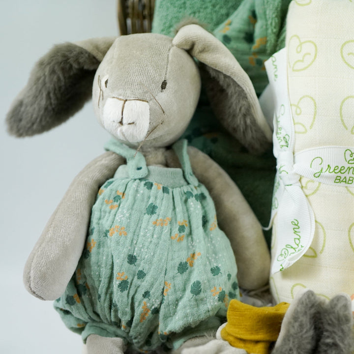 Luxury baby hamper with green hooded baby towel with ears, soft grey rabbit in green clothing set, rabbit slippers, cream and green baby swaddle, baby toiletries, green rabbit comforter, sophie la girafe teether toy, white baby sleepsuit with grey mice and magnetic fastenings all in a natural hamper basket 