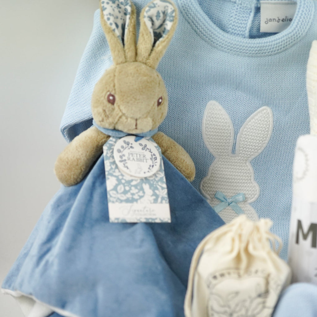 peter rabbit baby comforter , blue knit baby romper with bunny in a baby boy gift hamper