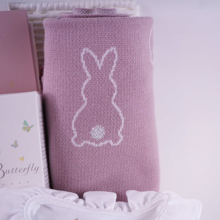 Pink knitted blanket with a bunny design on a white background