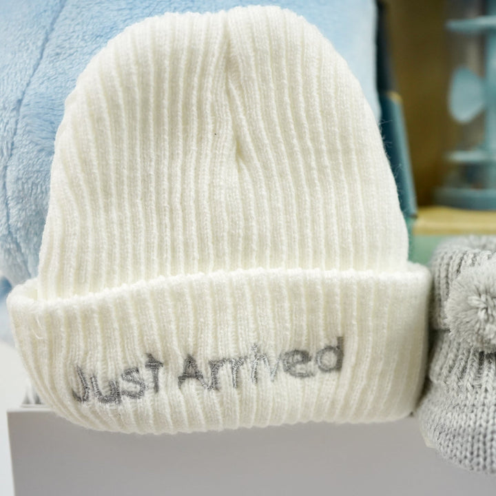 knitted baby hat in white with 'just arrived ' embroidered in silver 