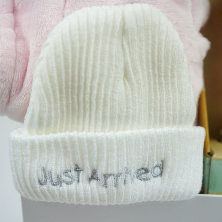 White baby hat with 'Just Arrived' text on a blurred background