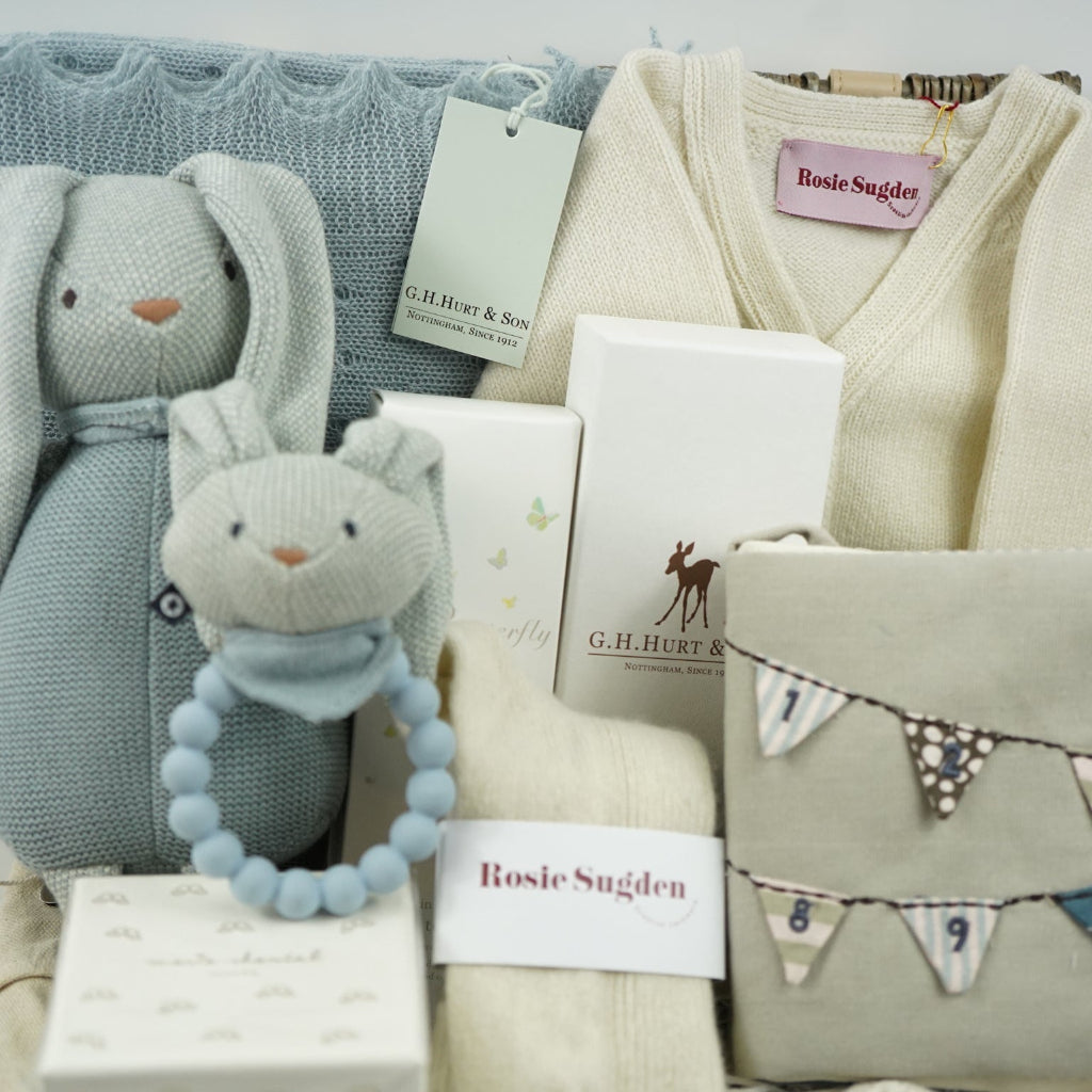 Baby gift set with soft toys, blankets, and cards on a light gray background