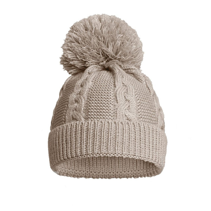 A light taupe knit beanie hat featuring a cable knit pattern, a ribbed cuff, and a fluffy pom-pom on top, shown against a plain white background.