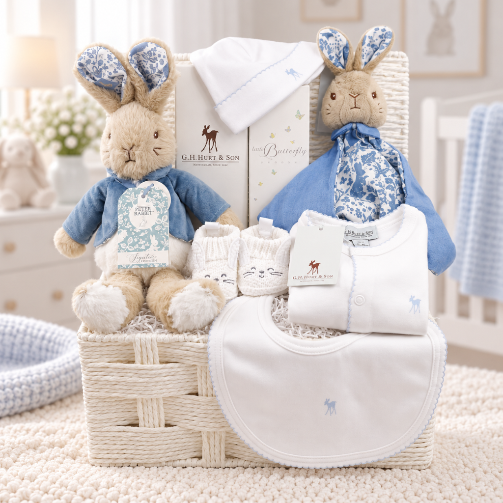 peter rabbit themed baby gift hamper in white basket, includes Peter rabbit soft toy and comforter, baby booties in white with bunny ears, luxury baby hairbrush, baby toiletries, luxury G.H.Hurt baby clothing set