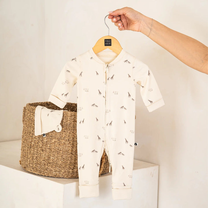Baby onesie with animal print on a hanger above a woven basket.