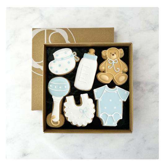 Box of baby boy themed biscuits  decorated with icing, rattle, bib, sleepsuit, teddy bottle and bootee shaped biscuit