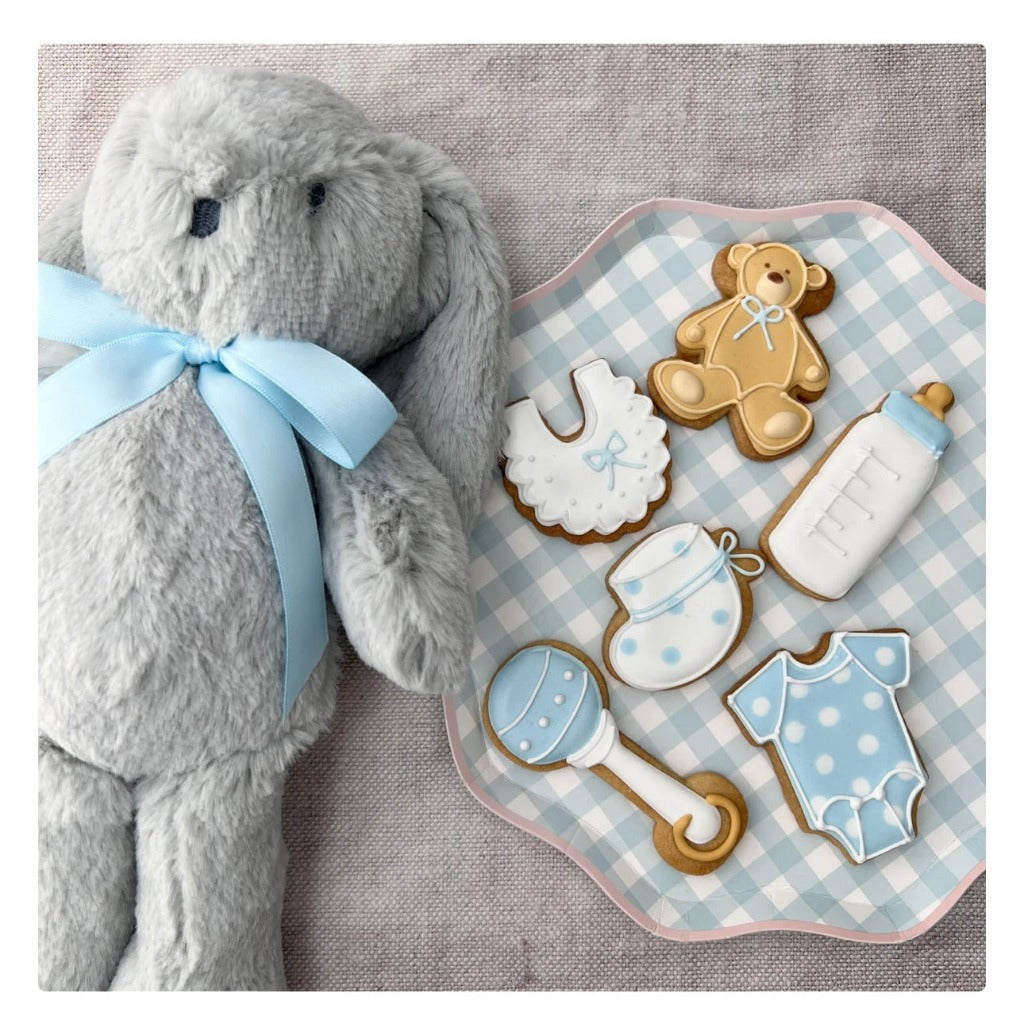 Box of baby boy themed biscuits decorated with icing, rattle, bib, sleepsuit, teddy bottle and bootee shaped biscuit