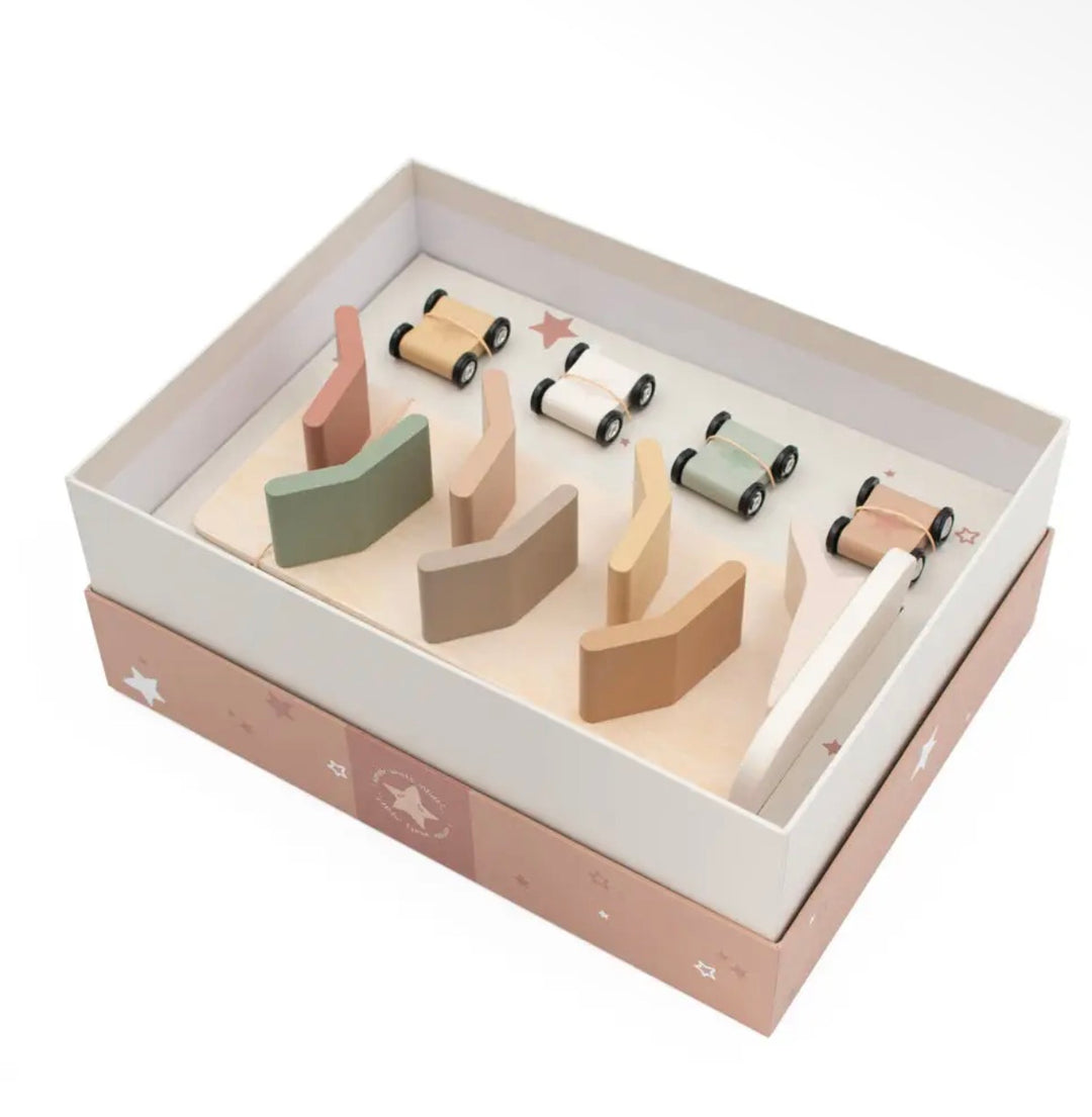 A wooden toy set in an open presentation box, featuring small toy cars with black wheels and curved wooden ramps in soft pastel colors including beige, pink, green, and brown, on a white background.