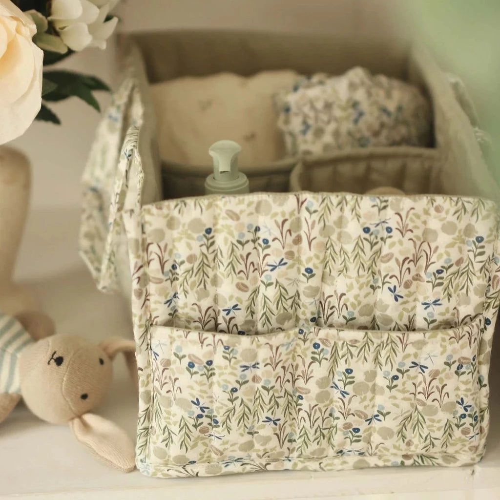 fabric nappy caddy with useful compartments in a white and neutral green with leaves and vines design