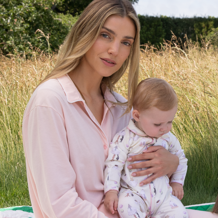 Vanilla coloured organic baby sleepsuit with pink edging and kitten pattern