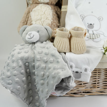 Hamper basket with baby items, soft tan koala, grey bubble teddy baby comforter, caramel coloured baby knit shoes, soft brown knit baby blanket, white baby set includes baby top with teddy and elephant, cute baby bottoms in white with teddy face and ears on the ankle cuff and teddy on the bum