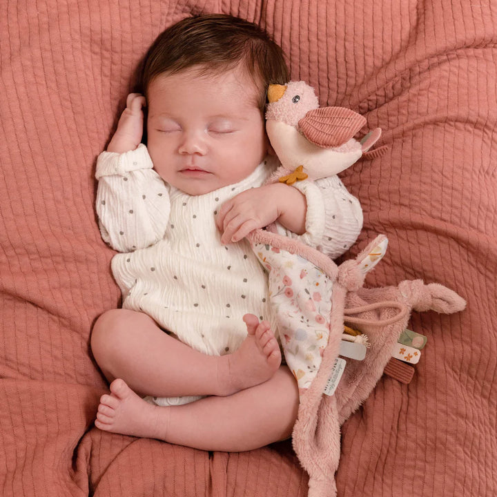 Baby cuddle cloth with a pink bird soft toy attached and sensory taggies