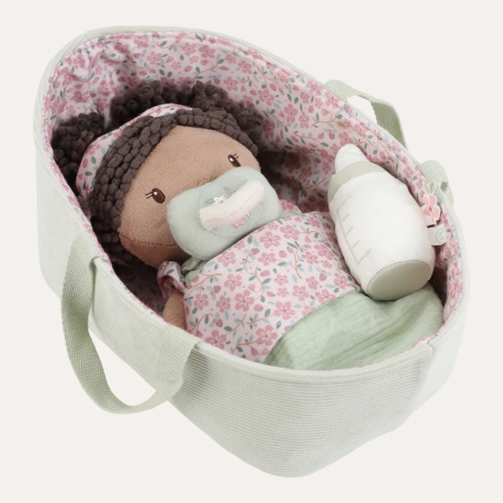 soft baby doll in a green fabric basket with a dummy, bottle and sleeping bag 