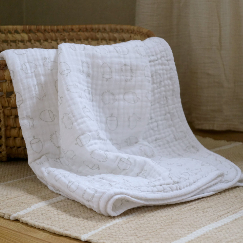 white muslin blanket with grey design woodland