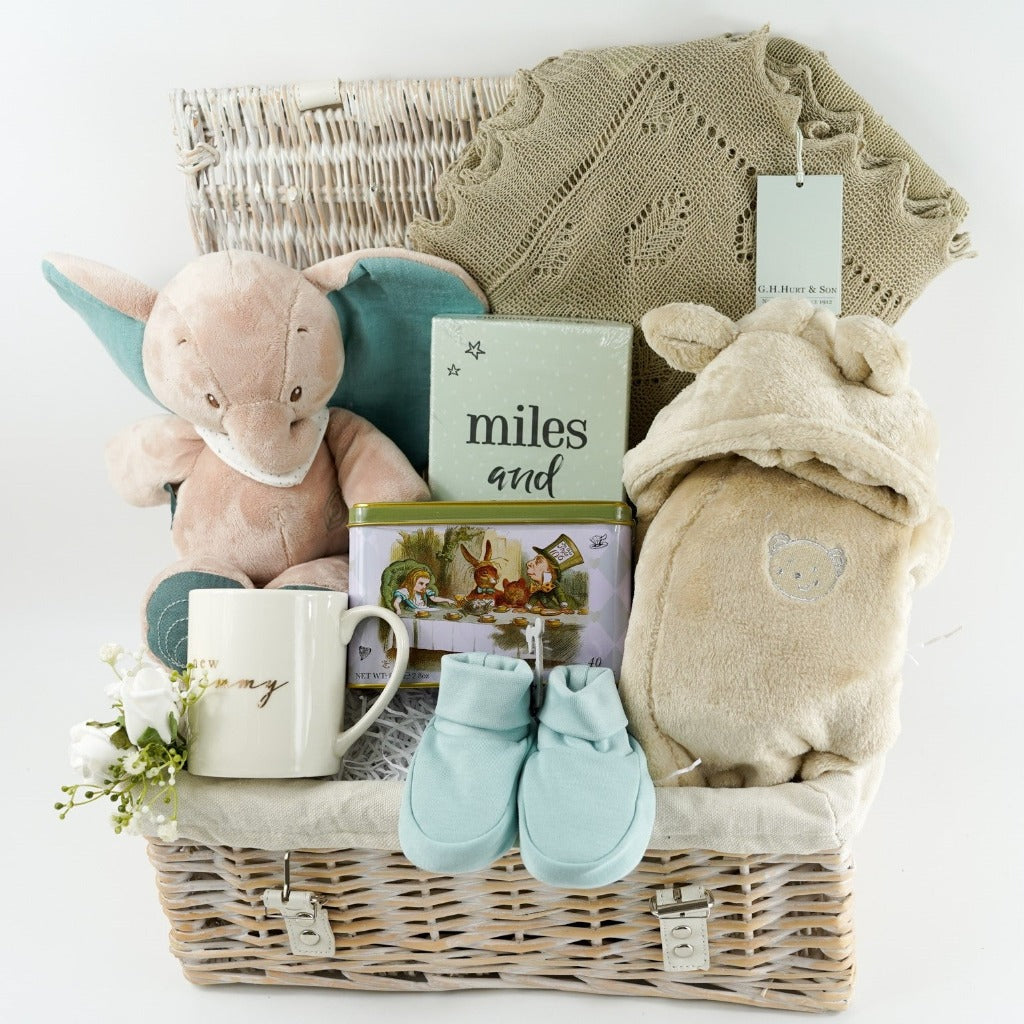 wicker hamper basket with new mum and baby gifts, new mum white mug, Alice in Wonderland tea caddy, baby memorable moments cards, Nattou soft cuddly elephant toy, G H Hurt shawl, baby dressing gown , baby organic slippers 