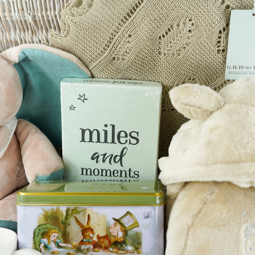 wicker hamper basket with new mum and baby gifts, new mum white mug, Alice in Wonderland tea caddy, baby memorable moments cards, Nattou soft cuddly elephant toy, G H Hurt shawl, baby dressing gown , baby organic slippers