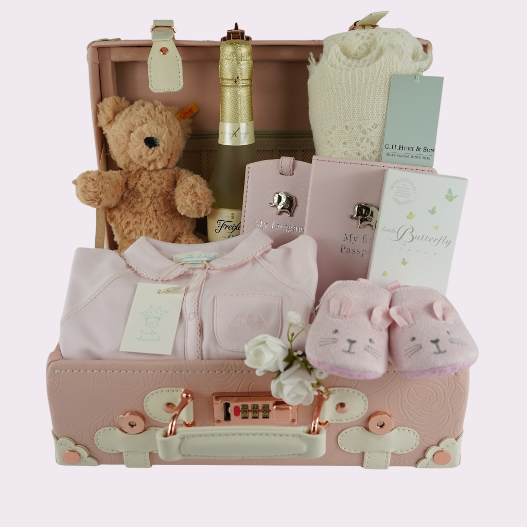 Pink baby suitcase with Steiff teddy, cashmere shawl, baby passport and luggage label, Marie Chantal  pink baby sleepsuit, pink baby slippers with bunny ears , Butterfly London baby massage oil