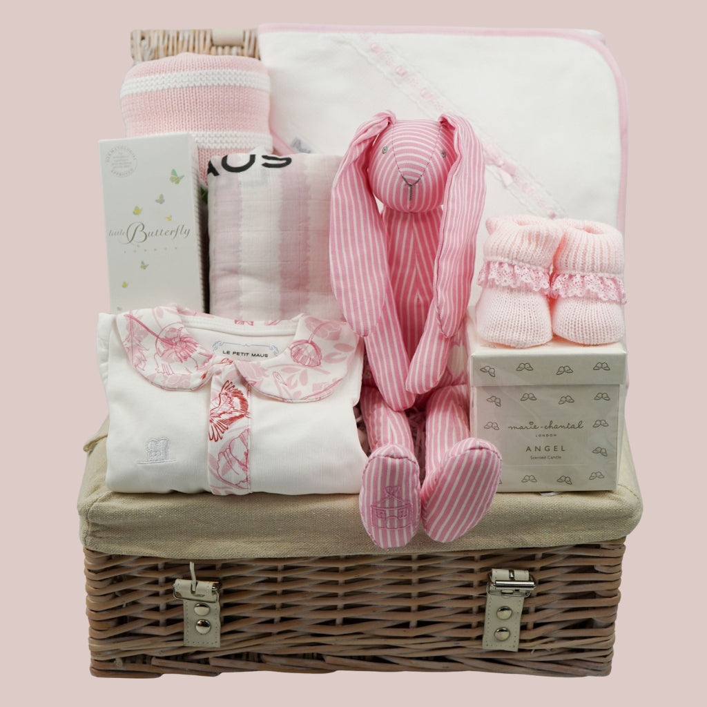 baby girl luxury hamper basket with organic baby sleepsuit with pink floral collar and trim, baby organic toiletries, cotton pink stipe baby blanket, pink stripe swaddle, white hooded towel with pink ribbon trim, pink booties, luxury candle for mum and pink stipe bunny soft toy rattle 