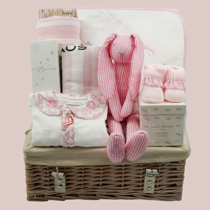 baby girl luxury hamper basket with organic baby sleepsuit with pink floral collar and trim, baby organic toiletries, cotton pink stipe baby blanket, pink stripe swaddle, white hooded towel with pink ribbon trim, pink booties, luxury candle for mum and pink stipe bunny soft toy rattle 