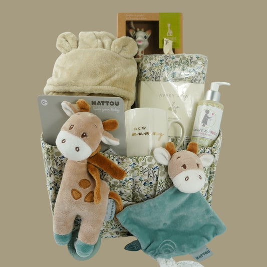 nappy caddy in cream, green and blue riverbank design full of new baby gifts,  baby dressing gown in caramel colour with cute ears, swaddle muslin to match the  nappy caddy, Sophie la girafe sensory teether, none china cream mug with mummy in gold, organic baby wash , nattou baby gifaffe  musical, nattou giraffe comforter