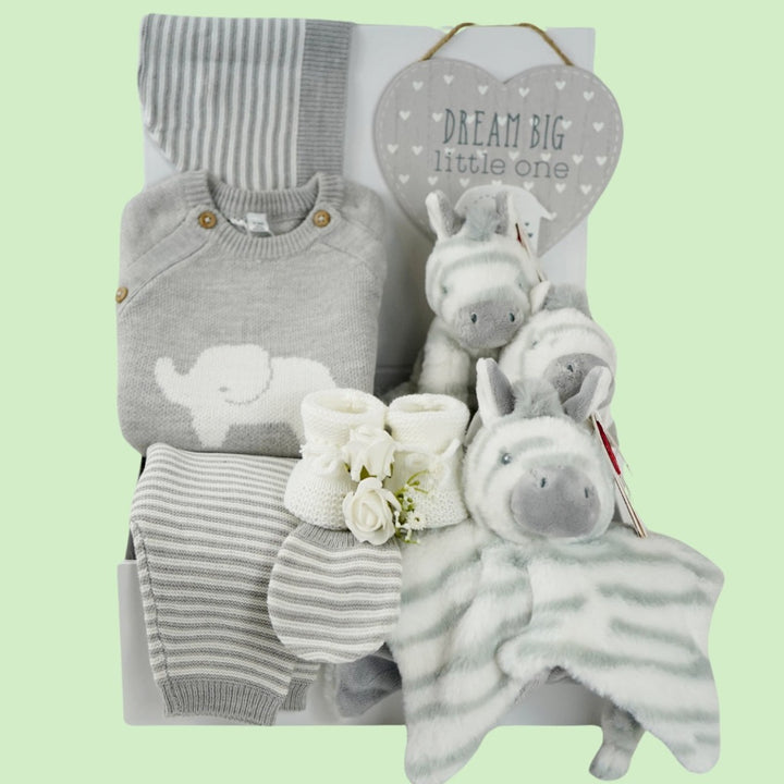 unisex baby hamper, grey knit elephant jumper, grey and white stripped leggings, grey and white hat and baby mitens, grey and white zebra comforter, baby rattle and plush zebra soft toy, white baby booties, grey baby nursery plaque