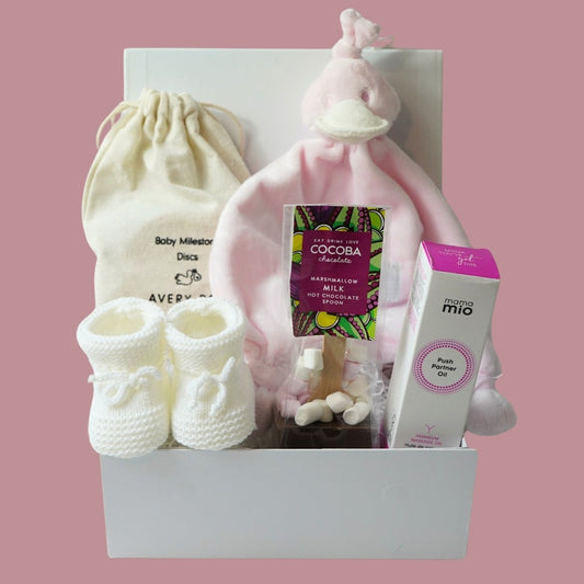pregnancy hamper with wooden pregnancy milestone discs in a draw string bag, white knit booties, pink BamBam duck tuttle,  perineum oil 
