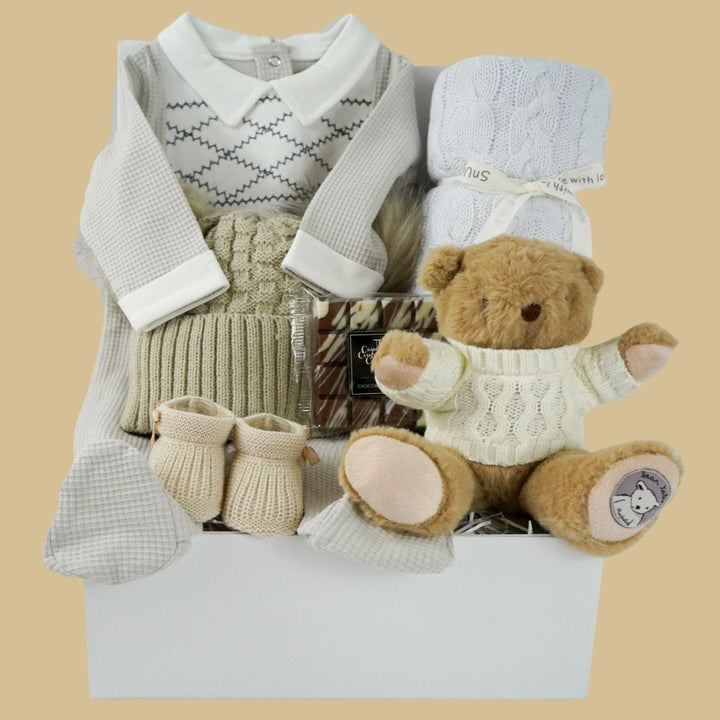 neutral baby hamper, spanish baby romper, white cotton baby wrap, baby booties, soft brown teddy with a jumper, chocolate slab