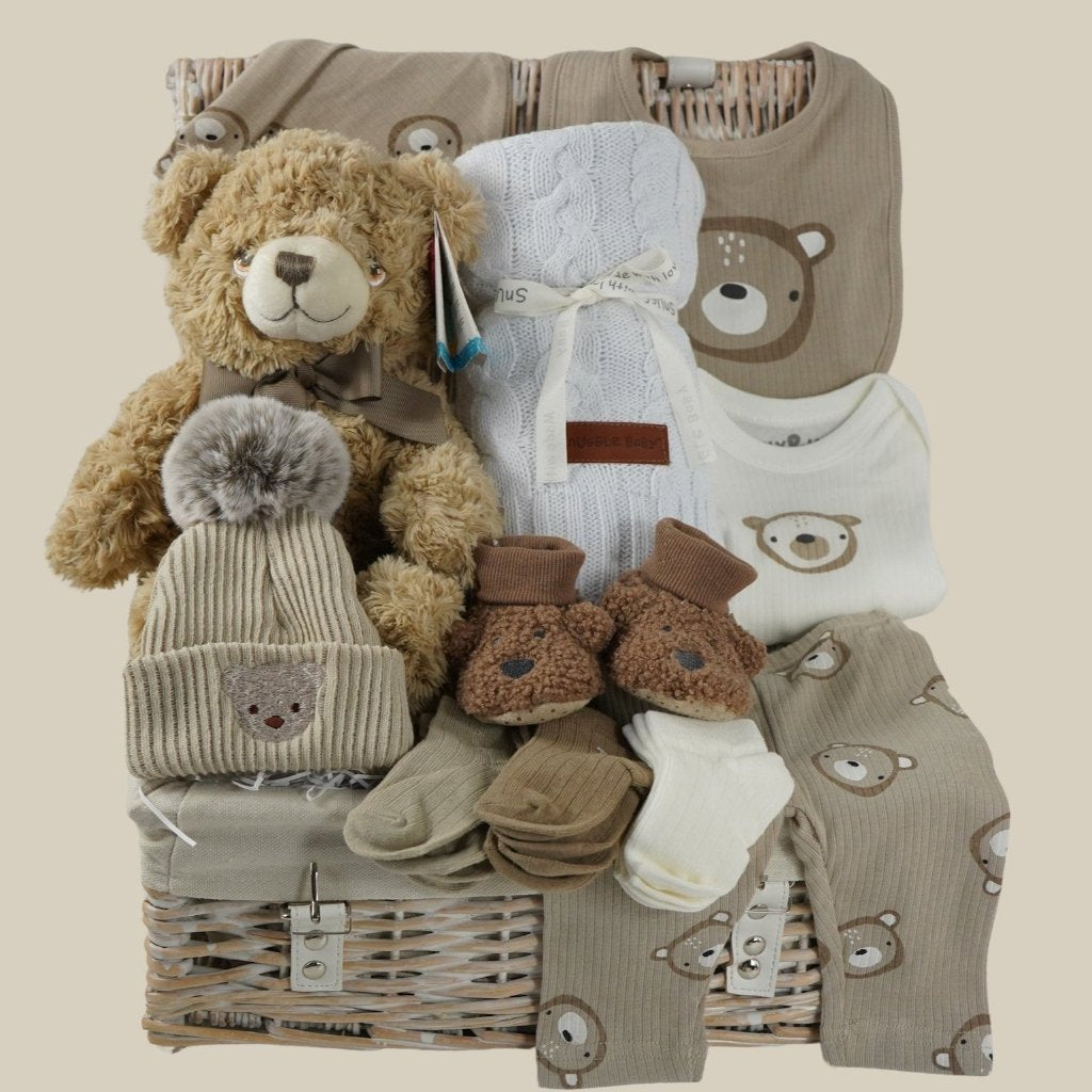 baby hamper with soft brown teddy, beige baby knit hat with embroidered teddy and pompom, white cable knit baby wrap, brown teddy bear slippers, 6 sets of baby socks in cream, brown and caramel, baby clothing set in caramel with teddy bears 