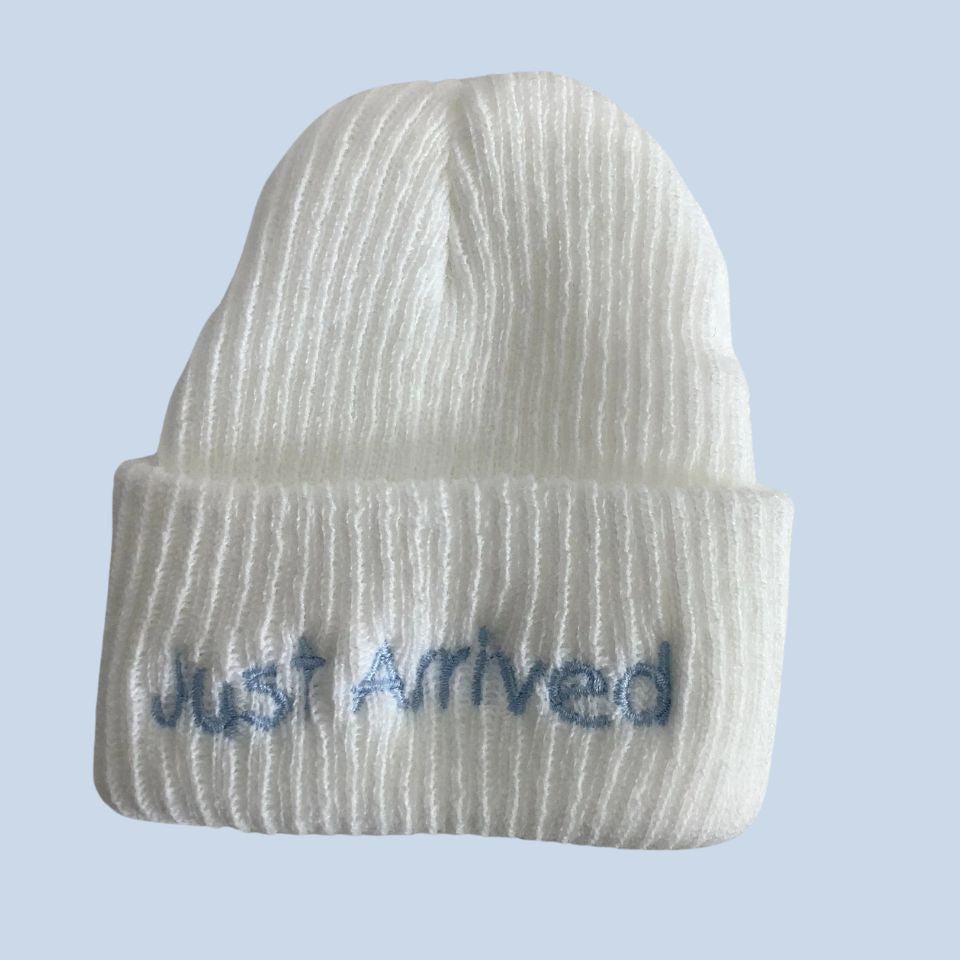 white baby beanie with blue  embroidered 'just arrived'