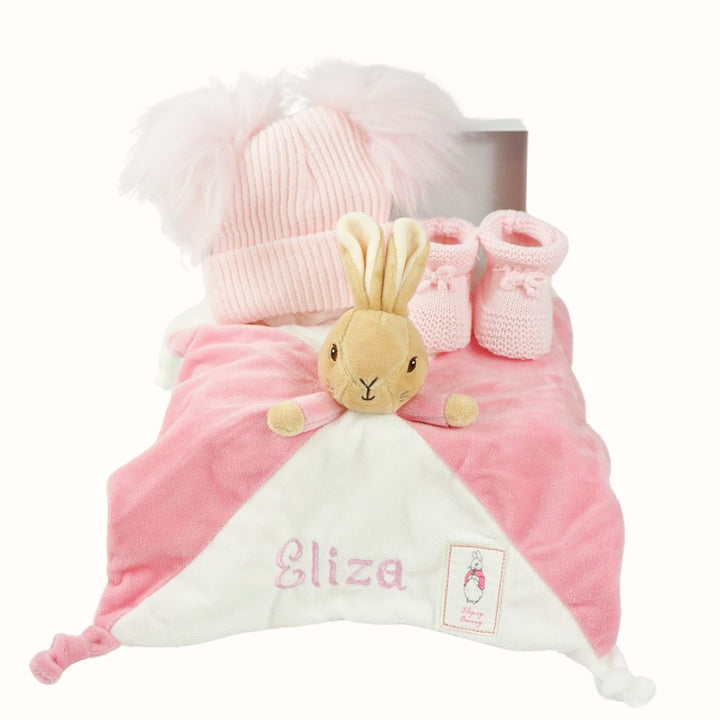 small white hamper box with beatrix potter pink bunny comforter with knot ends , pink booties and pink double pompom fluffy 