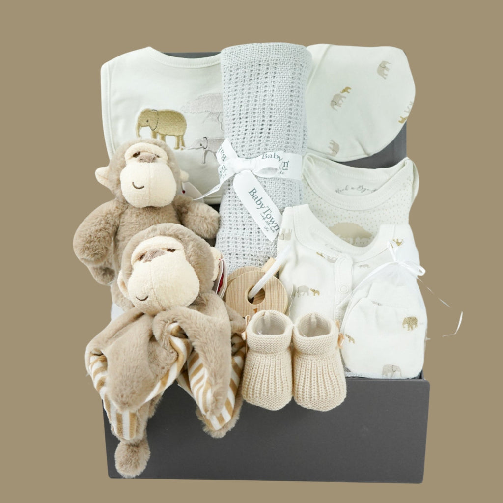 neutral baby hamper box, brown ecofriendly baby monkey comforter and matching soft toy, caramel coloured baby booties and wooden teething keys, grey soft cellular blanket, cream 100% cotton baby layette with embroidered elephants in brown and grey on the bib and printed elephants on the body