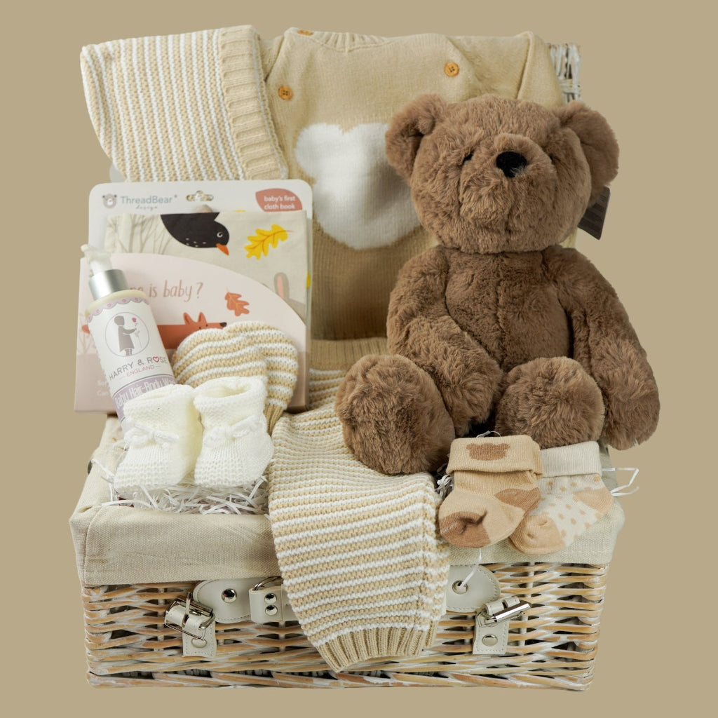 teddy bear themed baby hamper, beige and white baby knit clothing set with jumper, stripe knit leggings, hat and mittens, fabric baby book, 2 pairs of cream baby socks with teddy bear design , fabric baby book, baby shampoo and body wash, fabric book