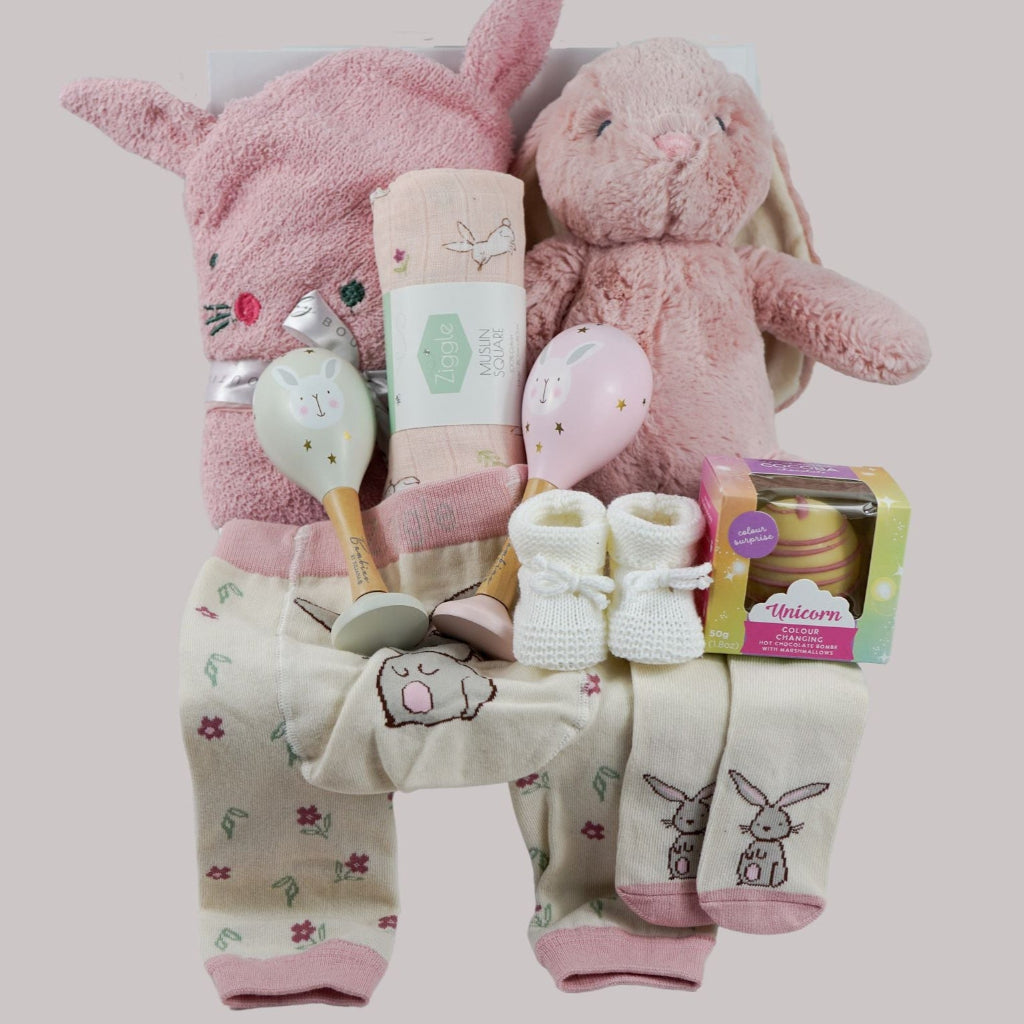 pink bunny baby hamper, pink hooded towel with bunny ears, soft bunny rabbit, bunny muslin, pink knit baby girl leggings with bunny on the  bum and matching socks with bunny, maracas in pin and grey with bunny face, white booties, , white chocolate bomb