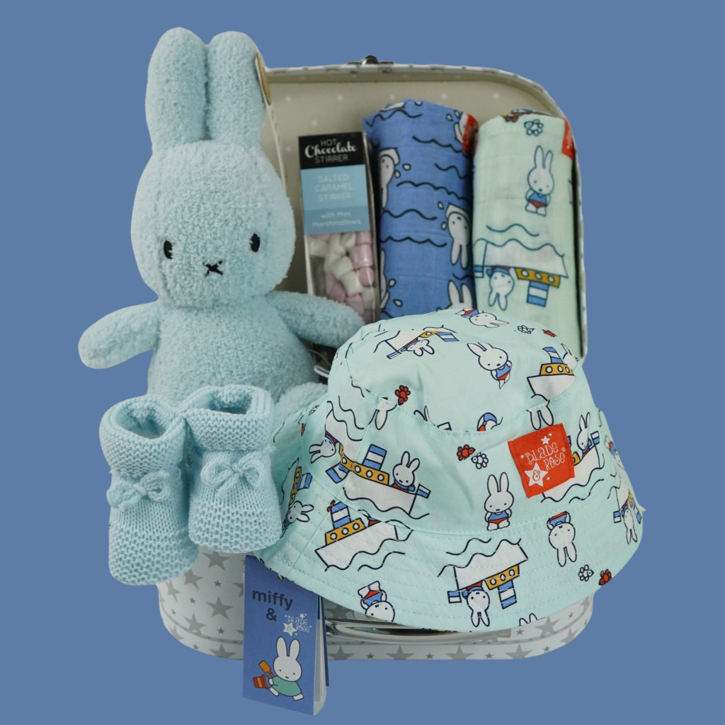White storage suitcase with soft blue terry Miffy, pale blue knit booties with tie, salted caramel chocolate stirrer, two muslins with Miffy pattern, bucket sunhat for baby with Miffy pattern