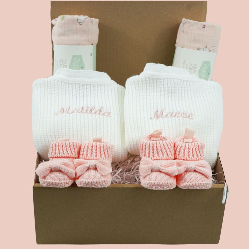 baby gifts in a eco friendly outer box includes white knit baby ribbed cardigans x 2 and pink booties with bows x 2 and pink muslin squares with bunnies x 2 