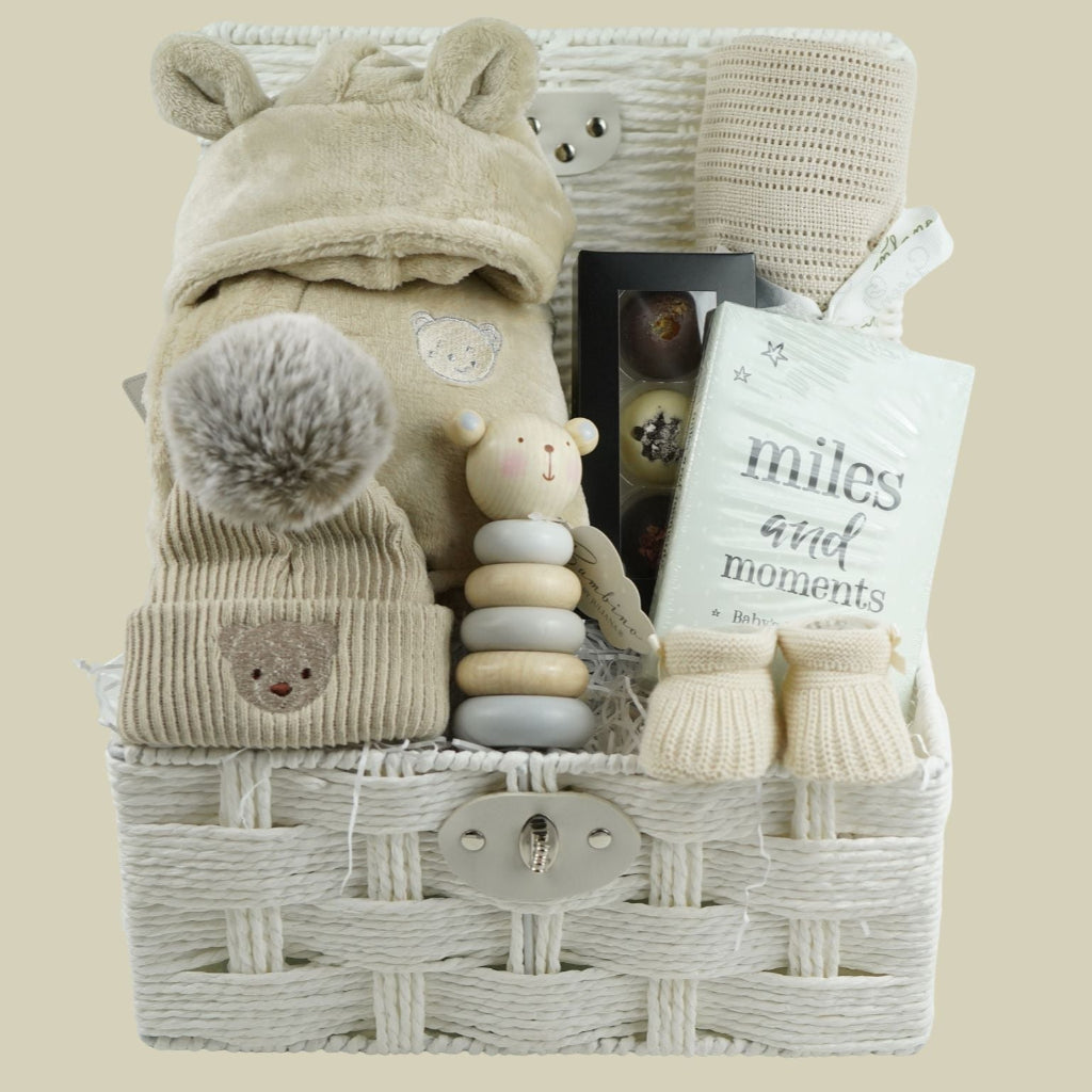 neutral baby and mum gift hamper includes neutral coloured baby dressing gown with cute ears, biscuit coloured baby pompom hat with teddy embroidery, wooden stacking toy, biscuit coloured baby booties, chocolates , milestone cards and bamboo cellular blanket 