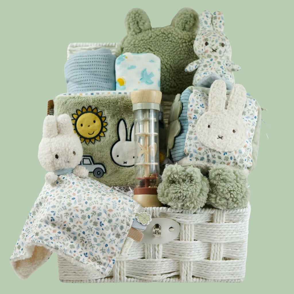 miffy themed baby hamper with green soft book, activity cube in pastel shades of green, white and blue, miffy soft rattle and matching comforter, rain rattle, blue cellular blanket, white muslin swaddle with bluebirds, fluffy green hat with ears and matching booties 